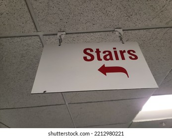 A sign attached to a ceiling stating where the stairs are located.