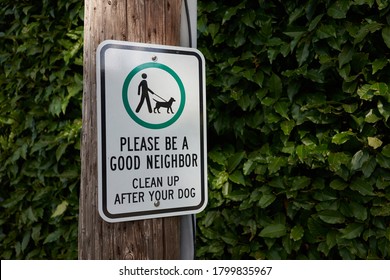 A Sign Attached To A Post On A Neighborhood Street Reminds Residents Of Cleaning Up After Their Dogs And Being Good Neighbors.