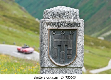 sign of the austrian county vorarlberg at the mountain road silvretta hochalpenstrasse, vintage car unsharp in the background