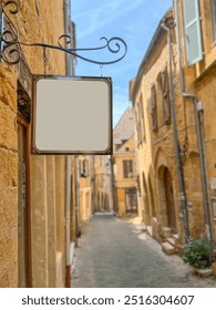 sign board, side view empty or blank notice board hanged on building entrance wall at narrow street in Europe. row of yellow houses or buildings in narrow street at small town. store entrance sign