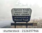 Sign closeup at Spruce Knob West Virginia mist fog autumn fall season by empty road for highest point in Monongahela national forest Appalachian mountains