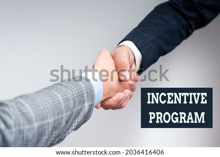 Sign displaying Incentive Program. Concept meaning specific scheme used to promote certain action or behavior Two Professional Well-Dressed Corporate Businessmen Handshake Indoors
