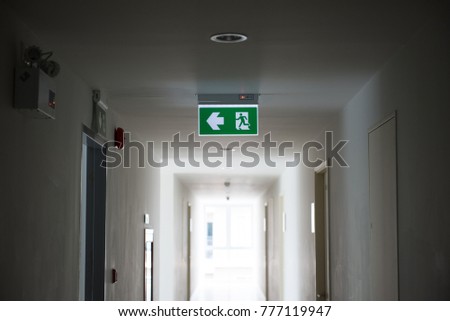 Sign : Emergency exit sign at path way indoor building public facility  that emergency escape route is left.  (fire, building, health or safety) require exit signs to be permanently lit.