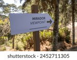 Sign in English and Spanish viewpoint and direction arrow on a trail in El Boqueron National Park forest.