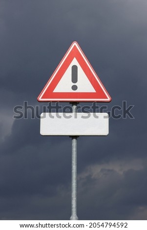 A sign with a exclamation mark warning for a dangerous situation ahead. At the bottom a smaller sign on which an editor can place a text