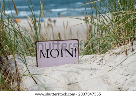 Sign with the German dialect word 'Moin' (Hello) in the sand dunes of an German island in the north sea.