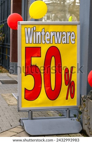 a sign with the german text fifty percent winter goods in front of a department store