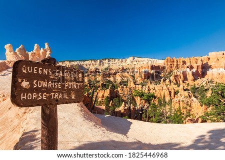 Sign giving directions for the most famous attractions of Bryce Canyon National park amphitheater area. In the background hoodoos and red rocks are visible during a sunny summer day
