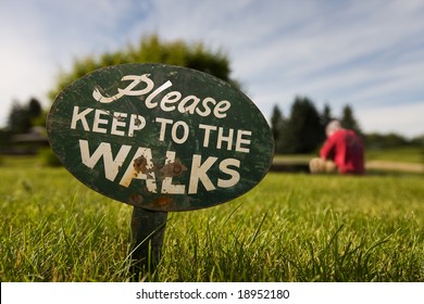 Sign In The Grass With A Man In The Background Breaking The Rules