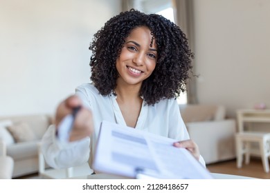 Sign Here. Young Smiling Confident Woman Pointing To A Contract, Sheet Of Paper, Holding A Pen, Looking And Showing It At Camera. Presentation, Agreement, Business Concept.