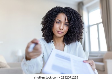 Sign Here. Young Smiling Confident Woman Pointing To A Contract, Sheet Of Paper, Holding A Pen, Looking And Showing It At Camera. Presentation, Agreement, Business Concept.