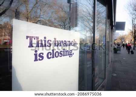 Sign in high street shop window ' This Branch is Closing'. Representative of a retail trend. 
