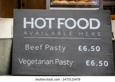 Sign - Hot Food Available Here - Beef Pasty Or Vegetarian Pasty - England In Window With Food In Background - Selective Focus