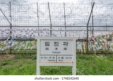 A sign for Imjingak train station along the North Korean and South Korean demilitarized zone. Flags and written notes are attached on the barbed-wire fence.

Translation: all text translated in image.