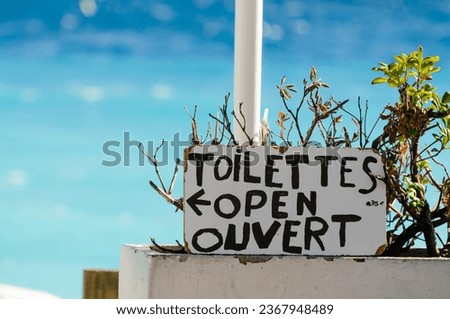 Sign indicating that seaside toilets are open in French and English: 