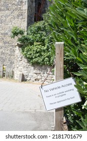 A Sign Instructing There Is No Vehicle Access Due To A Wedding. The Sign Which Is White With Black Writing Is Hung By Chain Off Of A Gate Post With Green Shrubs And A Stone Wall In The Back Ground.