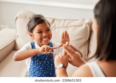 Sign language, learning and girl kid with her mother in the living room of their family home. Happy, smile and child speaking with her hands to her deaf mom to communicate in their modern house. - Powered by Shutterstock