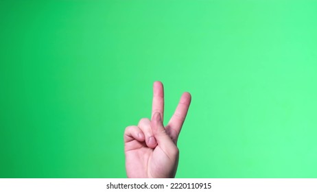 Sign language on the background of chroma key. Gesture of victory by male hand, green background - Powered by Shutterstock