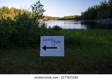 Sign learn to fish in the park, lake surrounded by boreal forest in the background out of focus, sunny summer day, blue sky. - Powered by Shutterstock