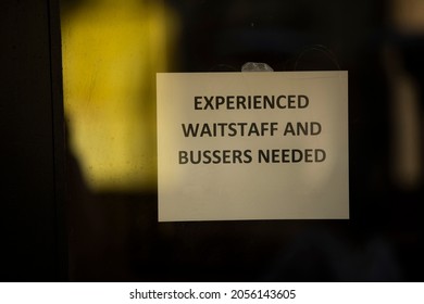 A Sign Looking For New Employees To Address A Shortage Of Workers Hangs In A Restaurant Window.