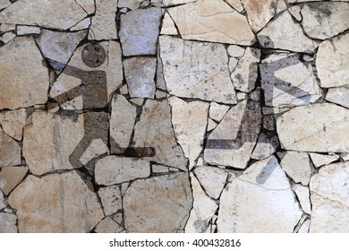 Sign Of Men And Women Running In Different Directions On The Background Of A Concrete Wall Divided By Cracks. Toned