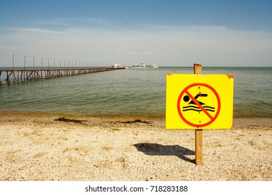 sign no swimming on the background of the sea and pier, a sign on a yellow background