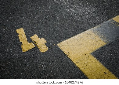 Sign On The Asphalt, Yellow Painted Number Four On Grey Street, Yellow Lines Like A Corner On The Road, Space For Text 
