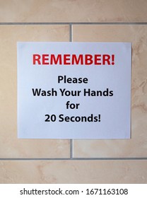 A Sign On A Bathroom Wall Saying REMEMBER! Please Wash Your Hands For 20 Seconds.  The Recommended Length Of Time To Protect Yourself From Viruses.