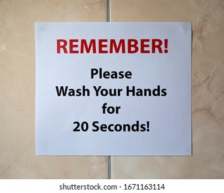 A Sign On A Bathroom Wall Saying REMEMBER! Please Wash Your Hands For 20 Seconds.  The Recommended Length Of Time To Protect Yourself From Viruses.