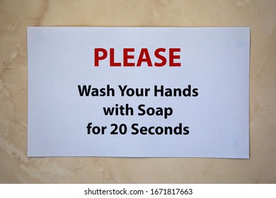 A Sign On A Bathroom Wall Saying PLEASE Wash Your Hands With Soap For 20 Seconds.  The Recommended Length Of Time To Protect Yourself From Viruses.