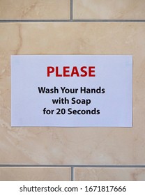 A Sign On A Bathroom Wall Saying PLEASE Wash Your Hands With Soap For 20 Seconds.  The Recommended Length Of Time To Protect Yourself From Viruses.