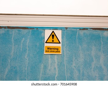 a sign on blue wall saying warning anti climb paint; England; UK