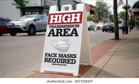 A sign on the sidewalk on a small town's main street warns people that this is a "high transmission" area for COVID-19. The CDC again required face masks when the delta variant surged in 2021. - Shutterstock ID 2017218107