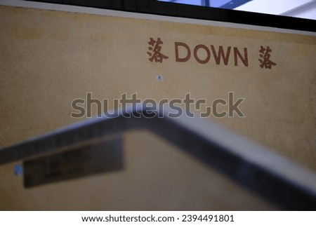 Sign on wall of landing Translation: DOWN (落) 商業照片 © 