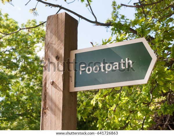 a sign on a wooden post saying footpath for walking\
outside in country close up english uk wayfaring directions for\
public use