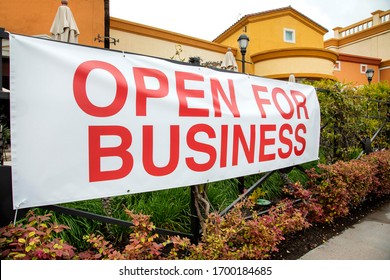 Sign Outside Shopping Mall Stating Open For Business With Red Capital Letters On White Background. Image Taken During Coronavirus Pandemic But Could Be Used For Positive Business Stories