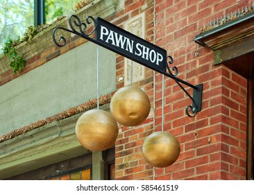 A Sign For A Pawn Shop With Three Hanging Gold Spheres. A Wrought Iron Bracket Is Attached To A Brick Store Front