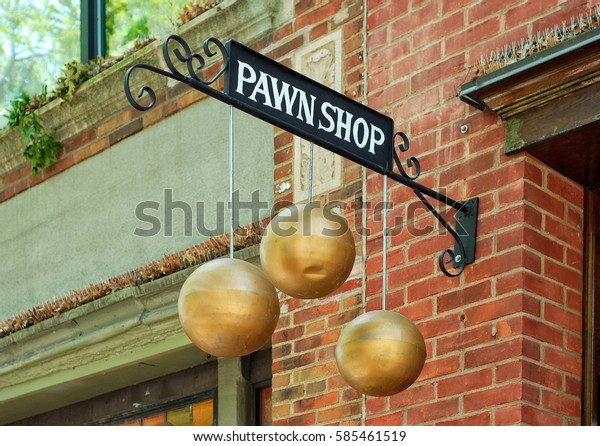 A sign\
for a pawn shop with three hanging gold spheres. A wrought iron\
bracket is attached to a brick store\
front