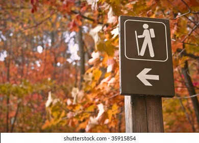 Sign Points To A Hiking Trail In Woods In Autumn