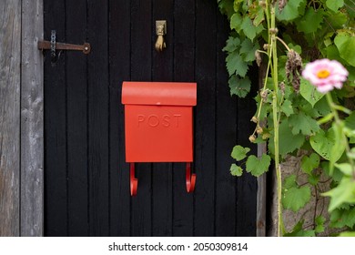 Sign Post On A Vintage Bright Red Metal Mail Box On A Black Wooden Door. Selective Focus.