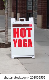 A Sign Reading Hot Yoga Outside On The Sidewalk