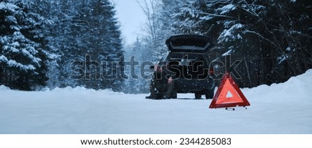 The sign is a red triangle on a rural winter snowy forest road. A broken-down car after the incident. The man took out a spare tire to change it Horizontal web banner with copy space.