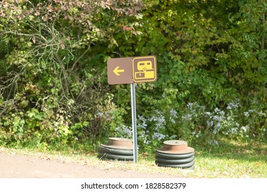 Sign for RV waste dump site.  Small brown sign with logo and arrow left near a campground.  Camping info sign at park. - Shutterstock ID 1828582379