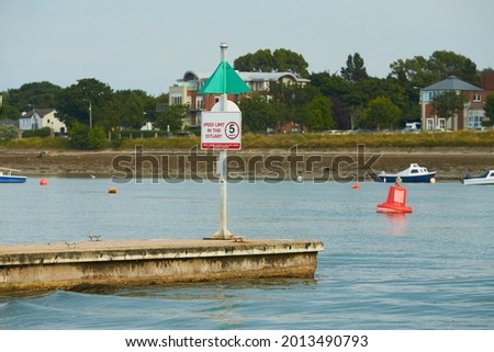 Sign saying to reduce speed to 5 knots, no wake zone at the entrance to Malahide Marina, Ireland.