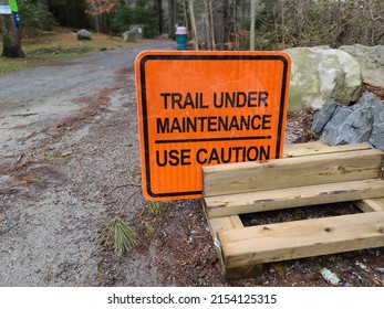 A Sign Saying That A Trail Is Under Maintenance And To Use Caution.