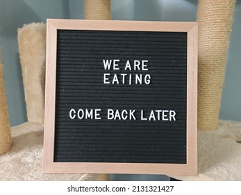 A Sign Saying We Are Eating Come Back Later. The Felt Sign Has Removable Letters Than Can Be Moved Around To Make Whatever Words Or Saying One Wants. 