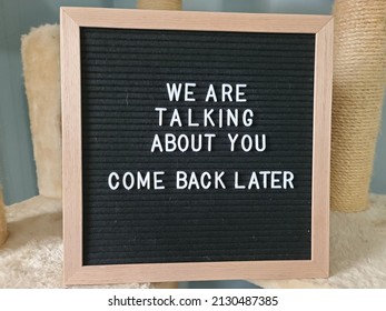 A Sign Saying We Are Talking About You Come Back Later. The Felt Sign Has Removable Letters Than Can Be Moved Around To Make Whatever Words Or Saying One Wants.