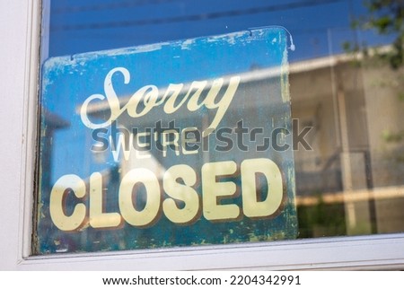 Sign in the shop window behind a pane of glass saying 'Sorry we're closed'. the shop is closed. end of business. closure of business. modern font.