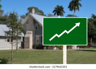 A Sign Showing An Upward Arrow In Front Of A House. Concept Of Increasing Home Prices And Value Or A Real Estate Boom.