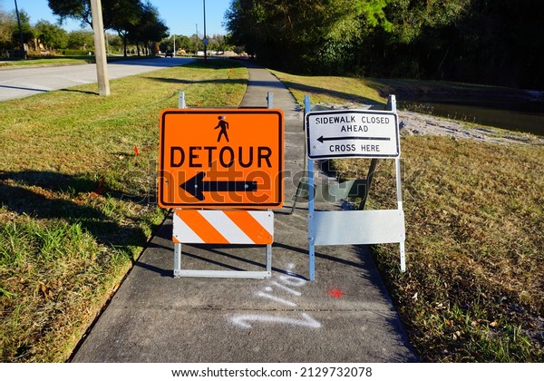 Sign shows that the sidewalk is closed and\
construction can be seen next to the\
street.